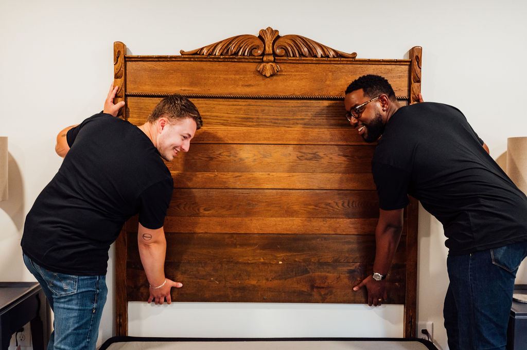 Two Loaders lifting a carved wooden headboard off the bed frame during removal