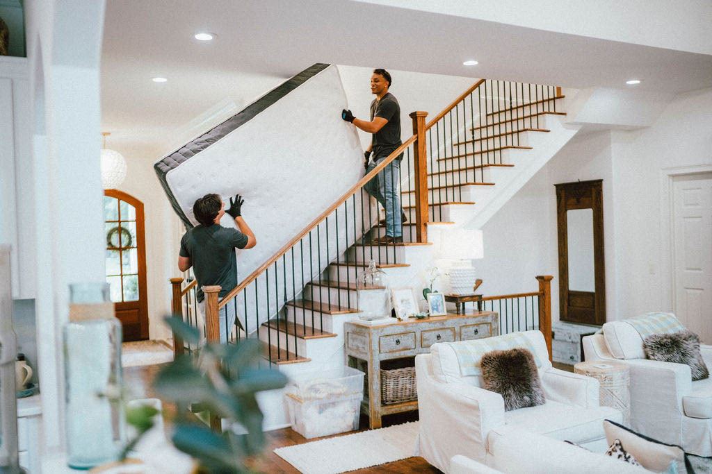 Loaders carrying a mattress down a staircase during an in home removal