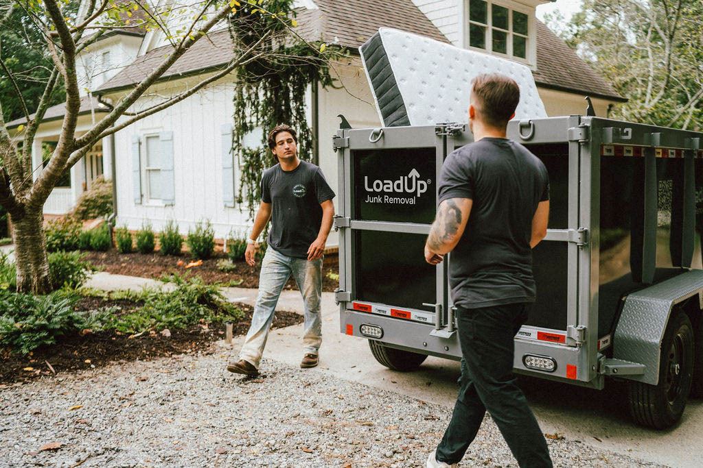 Loaders walking a mattress up the driveway toward the LoadUp trailer