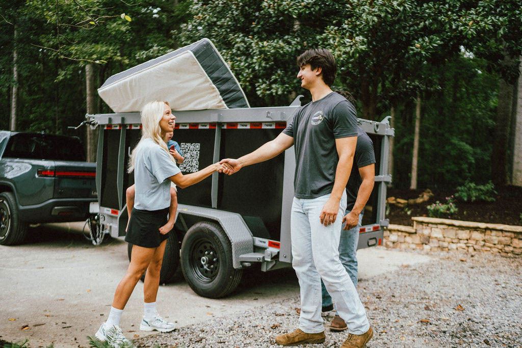 A Loader shaking hands with a customer while her old mattress sits loaded on the pickup trailer