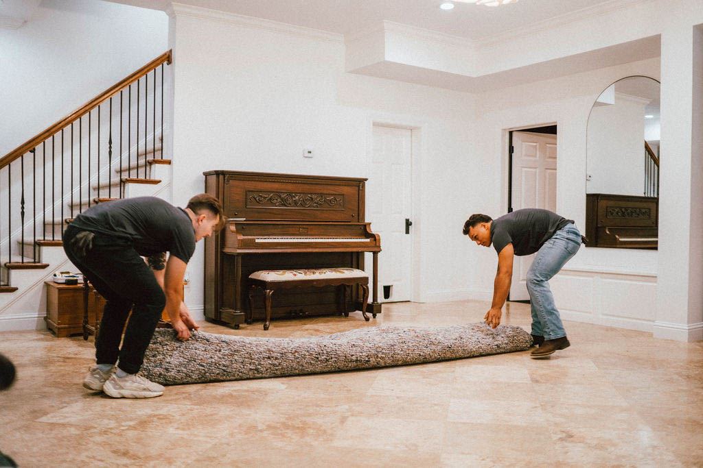 Two Loaders rolling up an area rug in a living room