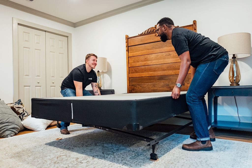 Two Loaders carrying a box spring out of a home