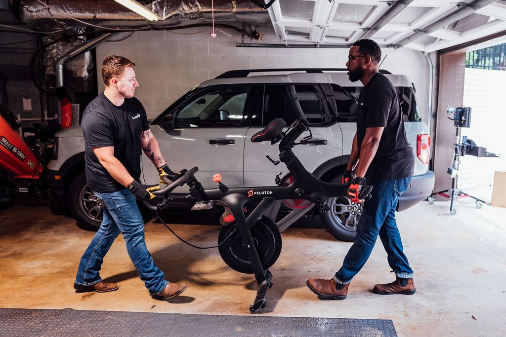 Two Loaders carrying an exercise bike out of a garage