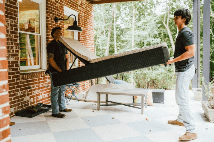 Two removal workers carefully maneuvering a large mattress.